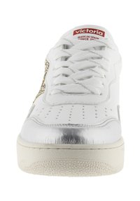 Sneaker bianca con una punta in argento texture, dettagli laterali dorati e una linguetta in tessuto con etichetta rossa "victoria".