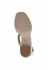 Sandal con tacco alto color beige con suola testurizzata, cinturino alla caviglia e dettaglio con fibbia. La suola presenta un design antiscivolo ed è leggermente più ampia nella parte della punta.