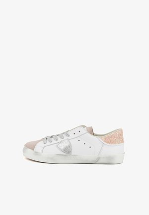 Sneaker bianca bassa con lacci argentati, punta in suede rosa, tallone glitterato color oro rosa, emblema a scudo e suola in gomma leggermente usurata.