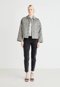 Veste à imprimé léopard gris avec un col, associée à un haut argenté, un jean noir et des sandales à talons noires avec des accents floraux.