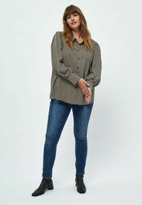 Black and cream patterned button-up shirt with long sleeves, worn with dark blue skinny jeans and black ankle boots. Smooth fabric texture.