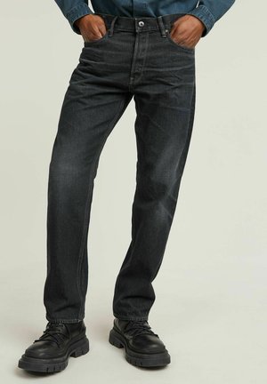 Dark wash denim jeans with a straight cut, five-pocket design, and contrasting stitching details. Paired with black lace-up boots.