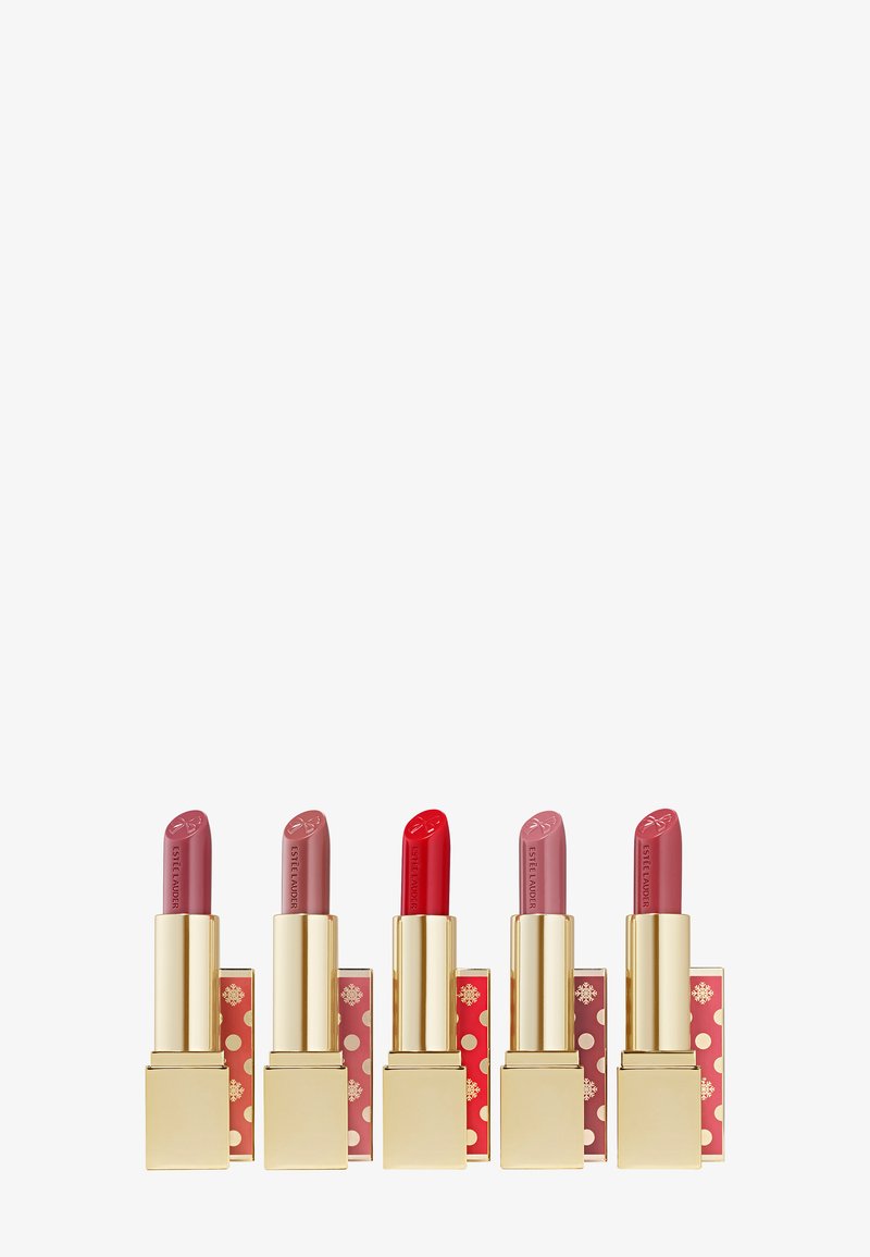 Cinque rossetti Estée Lauder in diverse tonalità di rosa e rosso, con astucci dorati e decorazioni festose in rosso e oro.