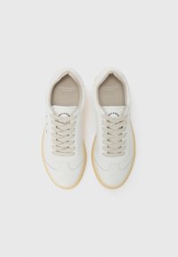 White leather sneakers with a smooth texture, beige laces, and rubber sole. Features branding on the inner lining and side.