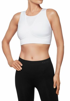 Witte sportbeha met een naadloos ontwerp en brede schouderbanden, gecombineerd met zwarte leggings met een subtiele logo op de tailleband.