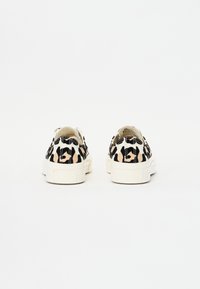 Zapatillas de lona con estampado de leopardo y suela de goma blanca, que presentan patrones en negro y beige y un diseño de punta redondeada.