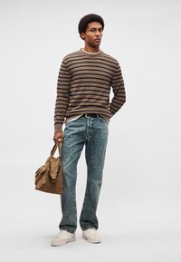 Καφέ και ναυτικό ριγέ πλεκτή ζακέτα, ανοιχτό μπλε τζιν τζιν, εκρού αθλητικά παπούτσια και καφέ υφασμάτινη τσάντα με χερούλια. Casual ντύσιμο, άνετη εφαρμογή.