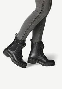 Black leather ankle boots with a textured fabric panel, lace-up front, side zipper, and chunky rubber sole. Silver-toned hardware accents present.