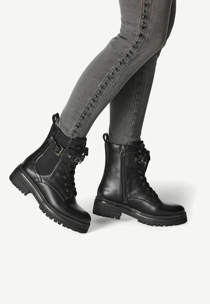 Black leather ankle boots with a textured fabric panel, lace-up front, side zipper, and chunky rubber sole. Silver-toned hardware accents present.