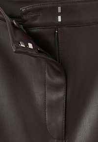 Bruine leren rok met een soepele textuur, ritsluiting en metalen hardwareaccenten op de tailleband. Visuele stiksels zijn zichtbaar.