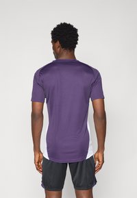 T-shirt med korte ærmer i mørk lilla med hvide sidepaneler, lavet af letvægtsmateriale, med en glat tekstur og tætsiddende design.