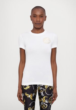 T-shirt bianca aderente con maniche corte, caratterizzata da un collo tondo e un logo circolare sul petto sinistro. Materiale in cotone morbido.