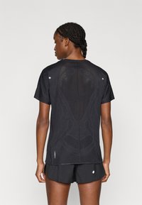 Μαύρο αθλητικό πουκάμισο με υφασμάτινη σχεδίαση από δίχτυ σε υφή, κοντά μανίκια και ανακλαστικές λεπτομέρειες. Συνδυάζεται με μαύρο σορτς στο κάτω μέρος.