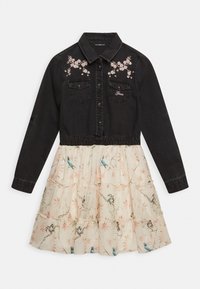 Czarna bawełniana bluzka z haftem kwiatowym, napami i dwiema kieszeniami na piersi; kremowa spódnica z warstwowymi falbanami, nadrukiem niebieskich ptaków i różowymi akcentami kwiatowymi.