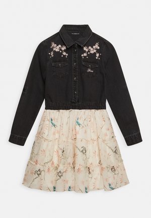 Top in denim nero con ricami floreali, bottoni a scatto e due tasche sul petto; gonna crema con balze a strati, stampa di uccelli blu e dettagli floreali rosa.