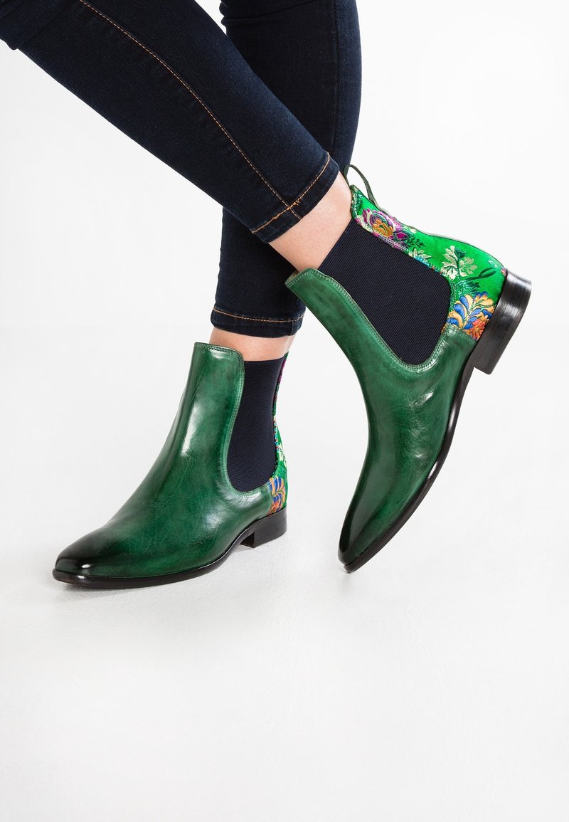 Botas de tobillo de cuero verde con un panel verde de estampado floral. Presentan un diseño elegante, punta afilada y tacón bajo. Superficie texturada visible.