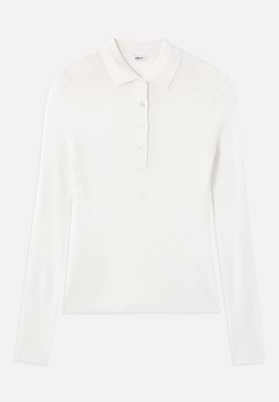Polo shirt bianco a maniche lunghe con texture a coste, dotato di una patta con tre bottoni e di un classico colletto abbattuto.