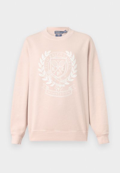 Sweat-shirt rose clair avec écusson blanc Polo Ralph Lauren sur le thème de Wimbledon, comprenant des raquettes de tennis et une couronne de laurier à l’avant.
