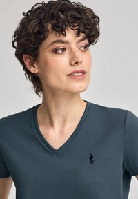 Donkerblauwe V-hals T-shirt met korte mouwen in katoenmix, met een klein zwart geborduurd logo op de linkerborst, gladde textuur.