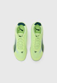 Des chaussures de sport jaune-vert vif avec une tige en mesh, des accents bleu marine et un logo Puma noir distinctif. Semelles arrondies pour une meilleure traction et un bon soutien.