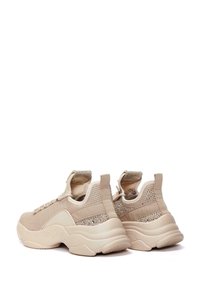 Beige athletic shoes with a textured knit upper, featuring glittery accents on the heel and a cushioned sole for comfort.
