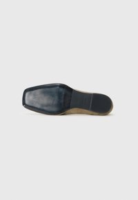 Semelle de chaussure en caoutchouc noir avec une surface lisse et polie. Présente une zone de grip texturée et une forme angulaire et rectangulaire. Les bords sont légèrement arrondis.