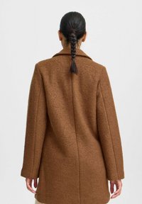 Bruine jas van een wollen mix met een gevarieerde textuur, brede kraag en lange mouwen. Heeft een ontspannen pasvorm en een rechte snit aan de achterkant.