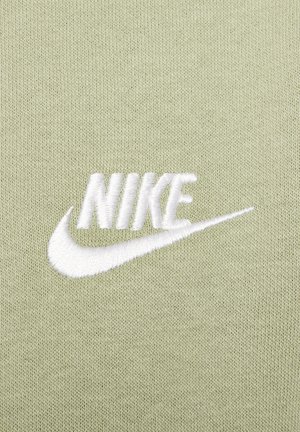 Un tissu vert clair présente un logo "NIKE" brodé en blanc avec un swoosh, mettant en valeur une texture lisse et un design minimaliste.