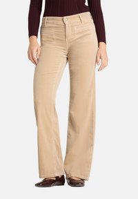 Pantalon en velours côtelé beige avec une coupe droite, doté de poches avant et d'une fermeture à bouton. Texture douce avec des nervures verticales.