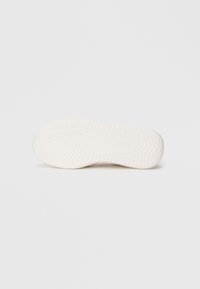 Hvid gummisål til sneakers med tekstureret mønster for godt greb og støtte. Glat overflade, rund form og minimale designfunktioner.