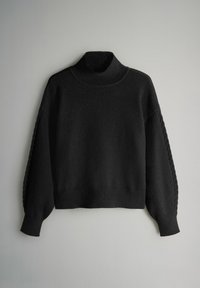 Musta neulepaita korkealla kauluksella, pitkät hihat, joissa on punottuja yksityiskohtia hihoissa, valmistettu pehmeästä, teksturoidusta kankaasta.