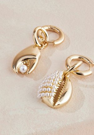 Zlato obarvani kovinski charms v obliki školjk, ena s perlom in druga okrašena z majhnimi belimi kroglicami, pritrjena na krožne zanke.
