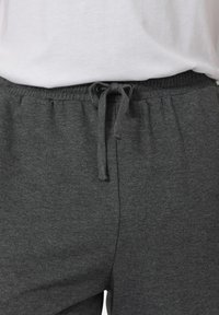 Dunkelgraue Jogginghose mit elastischem Bund und Kordelzug. Der Stoff wirkt weich, hat eine glatte Textur und keine sichtbaren Muster.