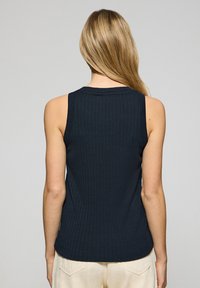 Marinblå ribbad linne med rund halsringning och ärmlös design. Har en nära passform och en slät yta utan synliga detaljer.