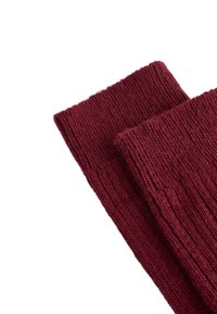 Bordeauxrode gebreide beenwarmers met geribbelde structuur en een omgeslagen bovenkant. Zacht garen zorgt voor warmte en comfort.