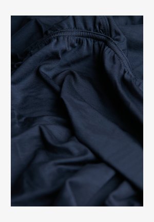 Navyblauwe stof met een gladde textuur, voorzien van verzamelde elastiek aan de randen, met zachte, vloeiende plooien die overal zichtbaar zijn.