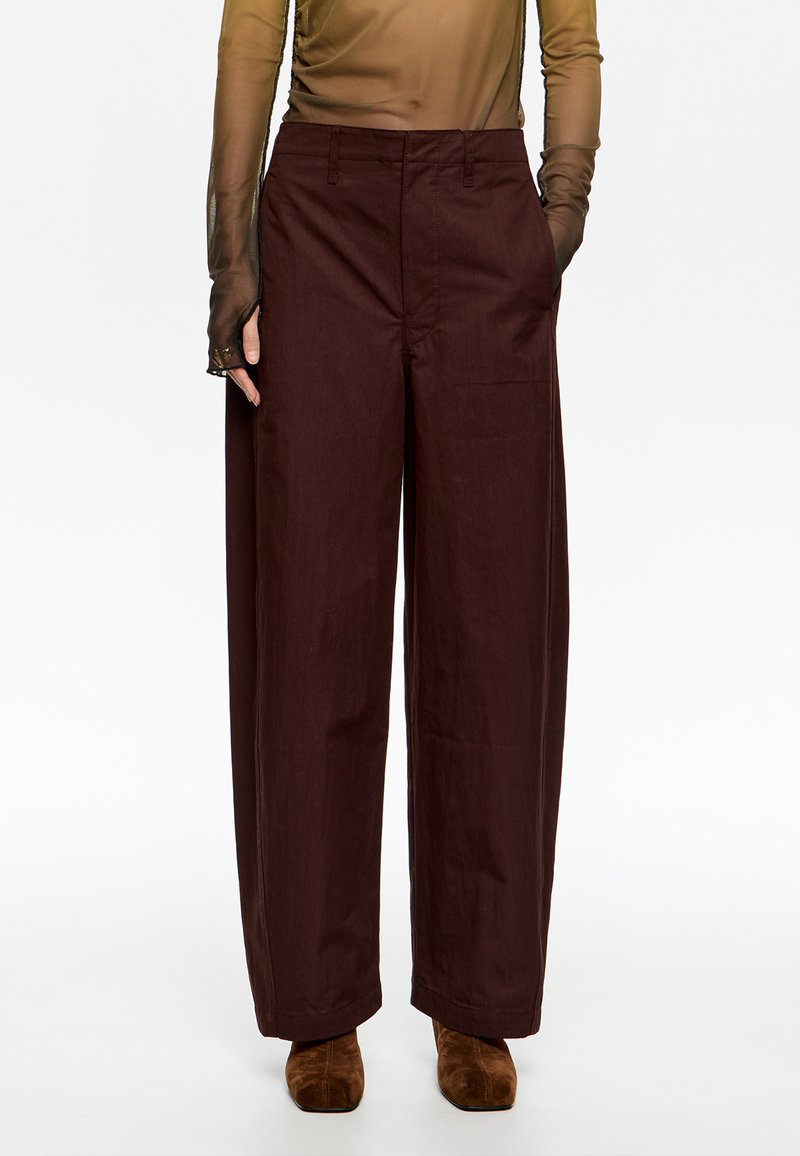 Laiene püksid sügavas burgundi värvi kangas. Omavad kõrget taljet ja küljetaskuid, sobitatud pruunide nahast ankle saapadega.