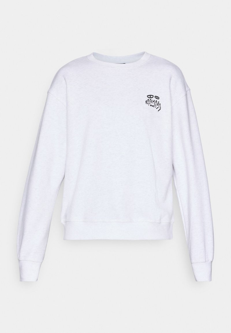 Sweatshirt blanc à manches longues et col rond, avec un petit graphique noir et un texte sur la poitrine gauche lisant "Karma" avec des yeux stylisés.