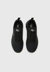 Black athletic shoes featuring a mesh upper, flat laces, a padded collar, and a textured rubber sole for grip and flexibility.