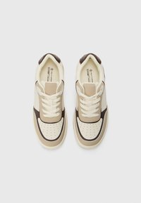 Beżowe i brązowe wegańskie sneakersy z perforowanym noskiem, kremowymi sznurówkami i kontrastowymi wstawkami, z wyściółką w kołnierzu i płaską podeszwą.
