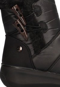Botín de invierno acolchado negro con forro de piel sintética, que cuenta con tres hebillas marrones y un acento metálico con la marca en el lateral.