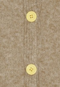 Beige uldstof med en blød tekstur, der har to gule plastikknapper i midten. Knapperne er runde med to huller hver.