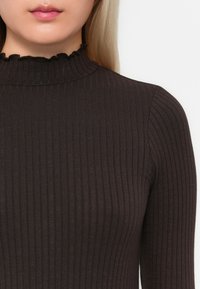 Mørk ribbete turtleneck topp med høy volangkrage og tilpasset silhuett, laget av et mykt, elastisk stoff.
