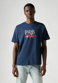 Camiseta de algodón azul marino con la palabra "PARÍS" en blanco y un diseño gráfico en rojo. Manga corta y cuello redondo.