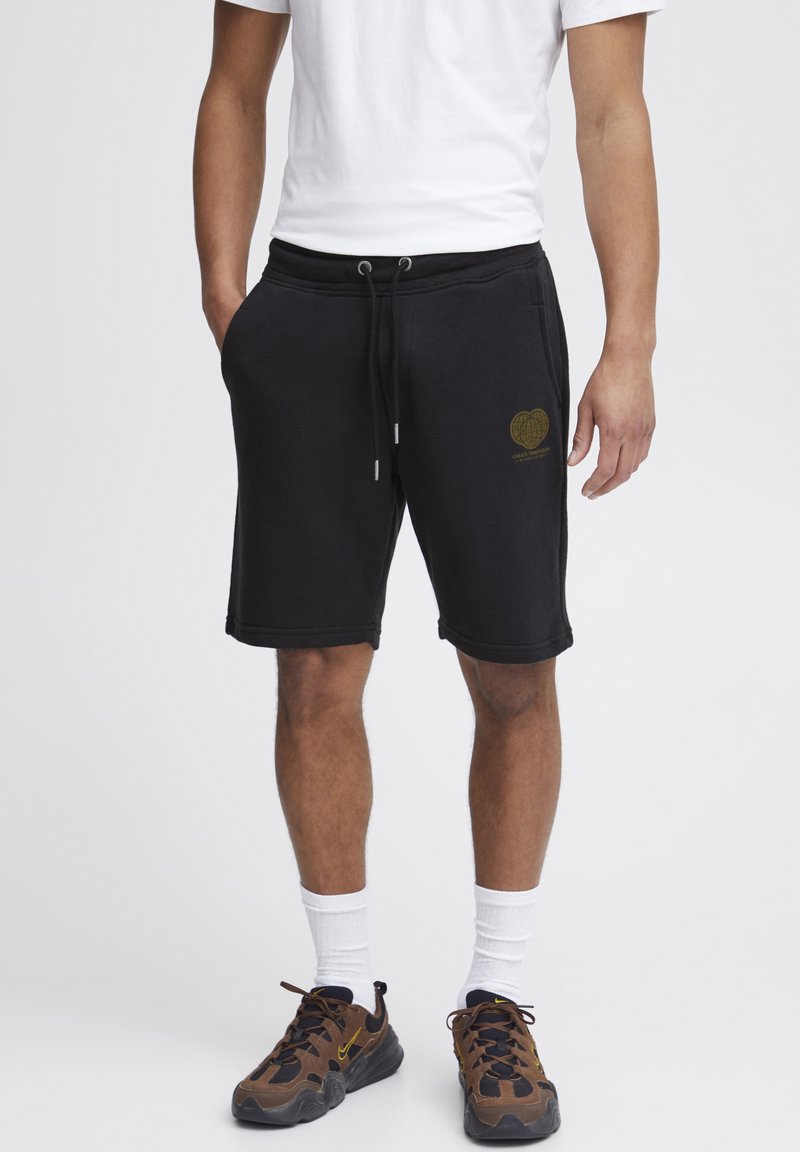 Schwarze Baumwollshorts mit elastischem Bund und Kordelzug. Mit einer goldenen Herzgrafik auf dem linken Oberschenkel. Mittlere Oberschenkellänge.