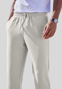 Hellgraue Sweatpants mit elastischem Bund und Kordelzug, ausgestattet mit seitlichen Taschen und einer glatten Textur.