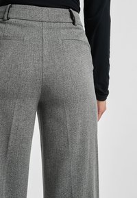 Grijze op maat gemaakte broeken met een gestructureerd patroon, met een hoge taille, riemlussen en achterzakken voor functioneel ontwerp.