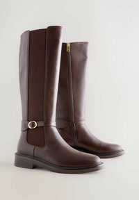 Bottes en cuir marron hauteur genou avec un panneau texturé, fermeture éclair sur le côté et détail de boucle en ton doré. Design à bout rond et talon bas.