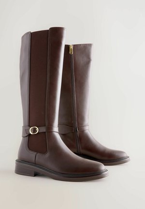 Bruine leren kniehoge laarzen met een gestructureerd paneel, een rits aan de zijkant en een goudkleurige gesp. Rond neus en ontwerp met een lage blokhak.