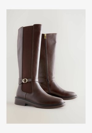 Bottes en cuir marron hauteur genou avec un panneau texturé, fermeture éclair sur le côté et détail de boucle en ton doré. Design à bout rond et talon bas.